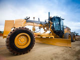 Large motor grader positioned at an outdoor construction site.