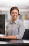 Customer service representative wearing a headset and smiling while working at a computer.