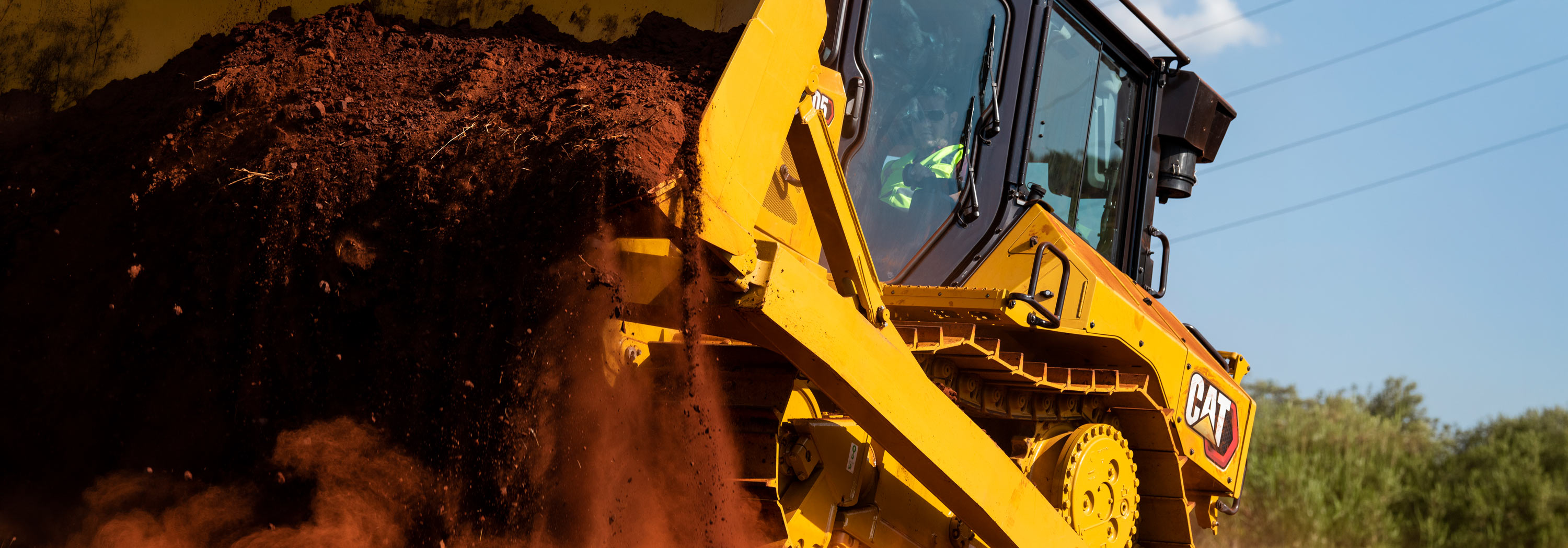 Caterpillar track loader moves a large load of soil at an outdoor worksite.