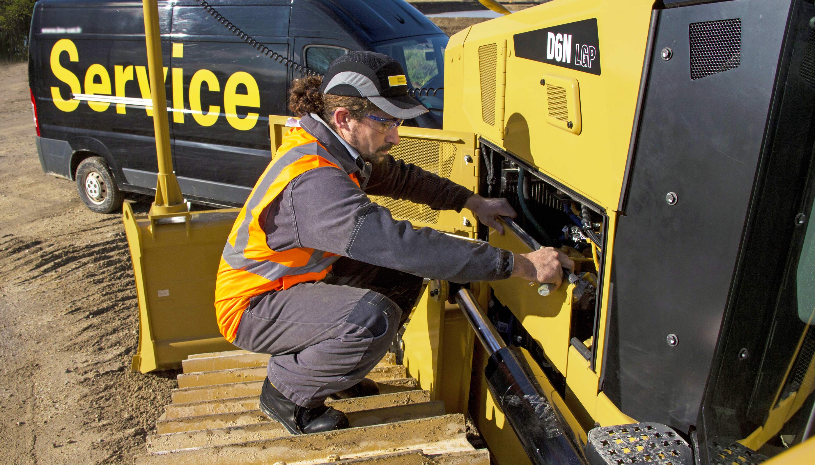 Service technician performs maintenance on a Caterpillar D6N dozer at a jobsite.