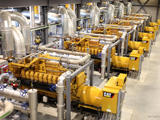 Rows of industrial generator engines and piping inside a power-generation facility.