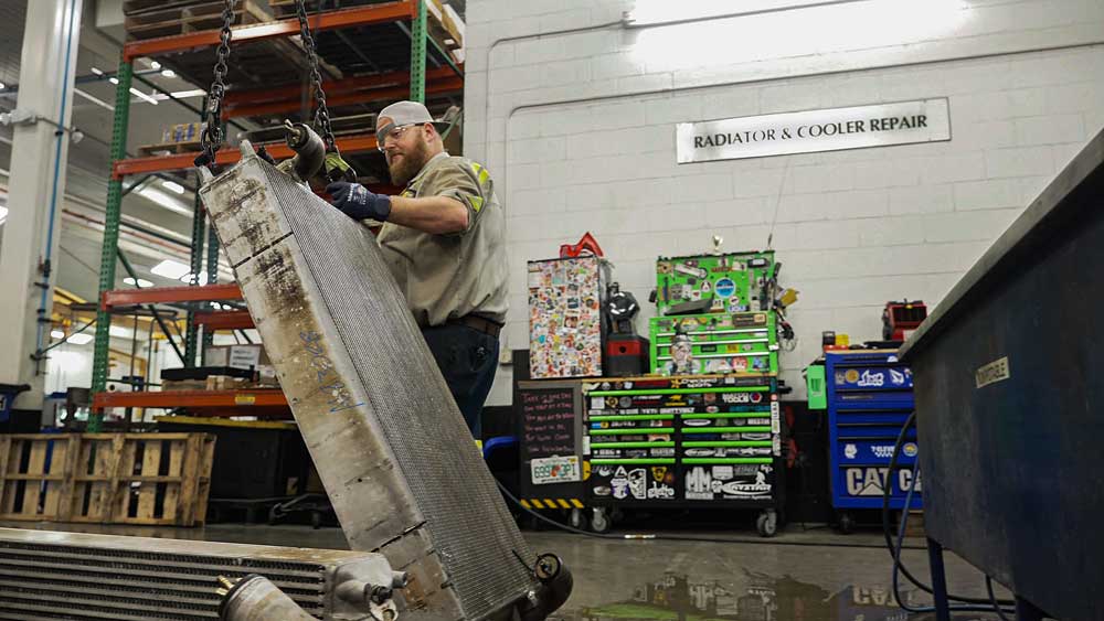 Technician working on a large radiator inside an industrial repair shop.